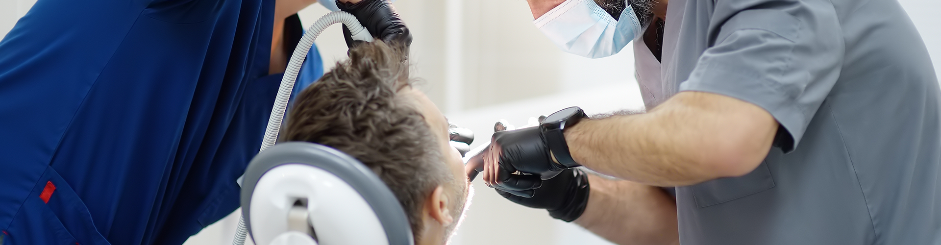 two dentists using dental tools in patient's mouth.